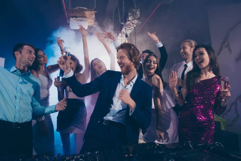Attractive, handsome man in formal wear dance with glass of beverage against crowd fancy luxury friends